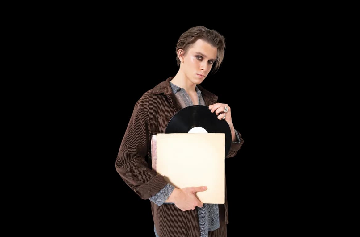 Artist holding a vinyl record and sleeve against a black background.